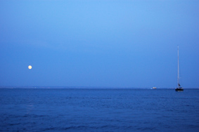 Favignana: sorge la Luna, sullo sfondo Marsala  appena visibile.
